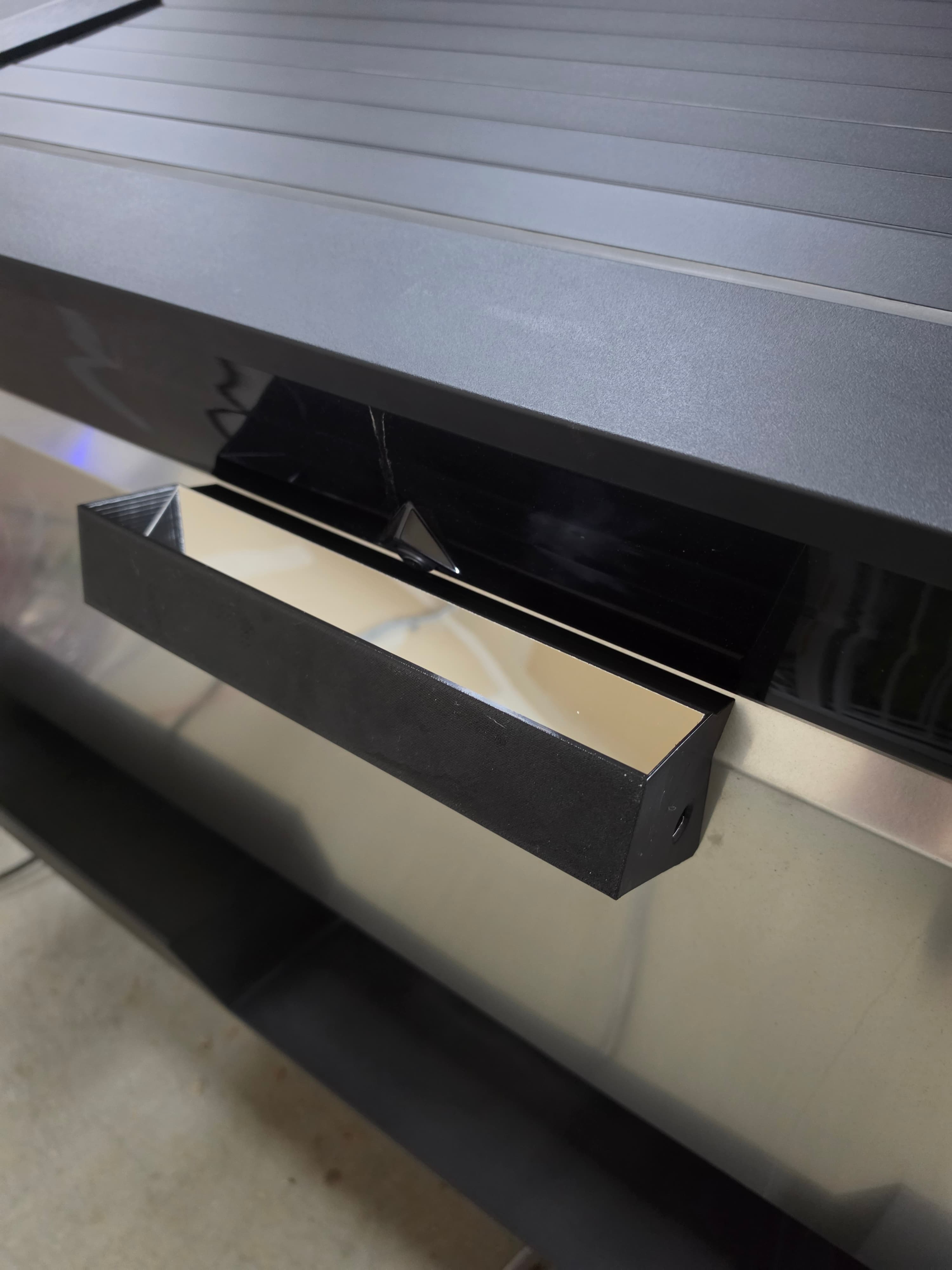 Modern black rectangular handle mounted on a reflective surface with grey vertical slats.